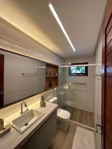 a bathroom with a sink and a toilet and a mirror at Reserva BG - Apto Brisa da Barra - Frente mar in Barra Grande