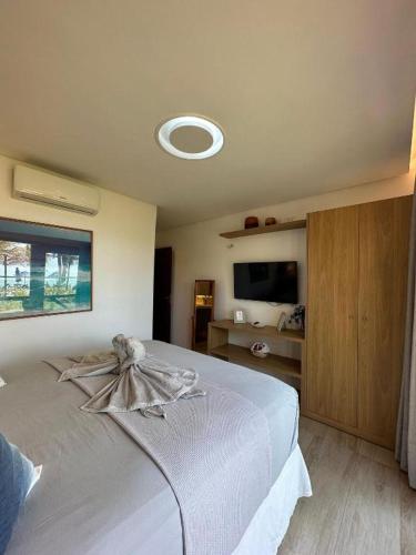 a bedroom with a white bed and a tv at Reserva BG - Apto Brisa da Barra - Frente mar in Barra Grande