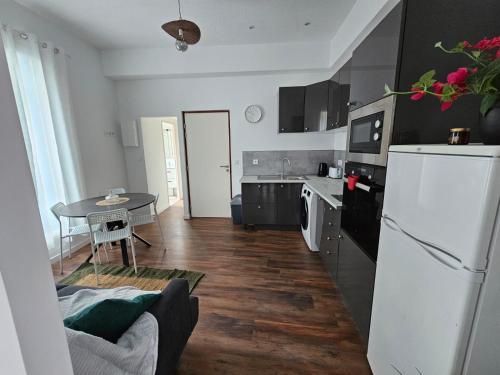 a kitchen with a white refrigerator and a table at Les sureaux, le charme du centre de perpignan in Perpignan