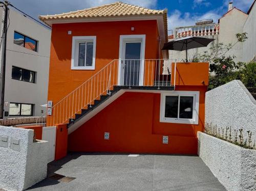 a orange house with a staircase in front of it at Casa da Vila in Machico