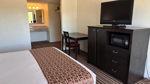 a hotel room with a bed and a flat screen tv at Ambassadors Inn & Suites in Virginia Beach