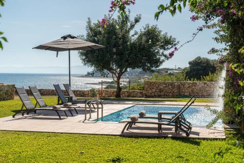 a pool with two lounge chairs and an umbrella at Villa Brio in Skala Kefalonias