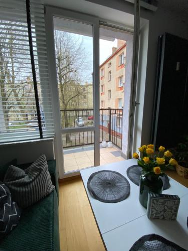 a living room with a table and a large window at Apartament Starówka in Koszalin