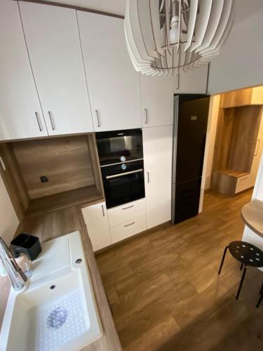 a kitchen with a sink and a black refrigerator at Apartament Starówka in Koszalin