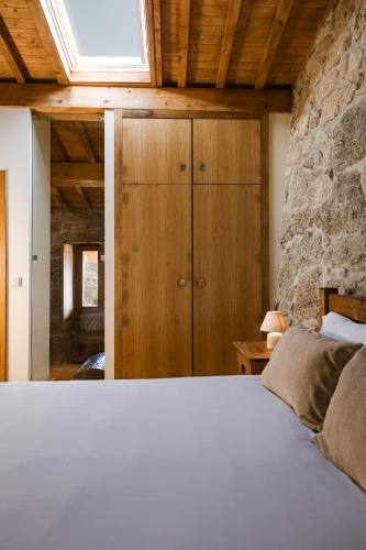 a bedroom with a white bed and a stone wall at Quinta da Portela - Casa Visconde Arneiros - by RowdHouses in Lamego