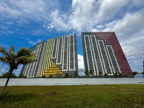 two tall buildings with a palm tree in a park at Apartamento em Praia de Cotovelo in Parnamirim