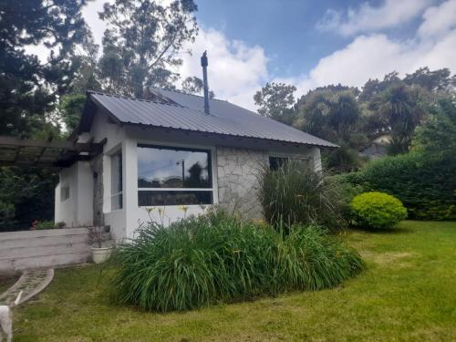 a small white house with a window in a yard at La Juanita in Sierra de los Padres