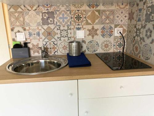 a kitchen counter with a sink and a tile wall at BananaHouse in Kefallonia