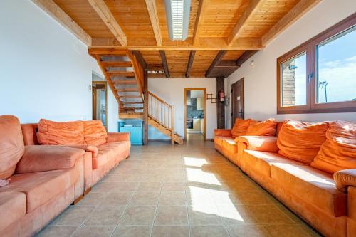 a living room with orange couches and wooden ceilings at Can Prats in Ríudecañas