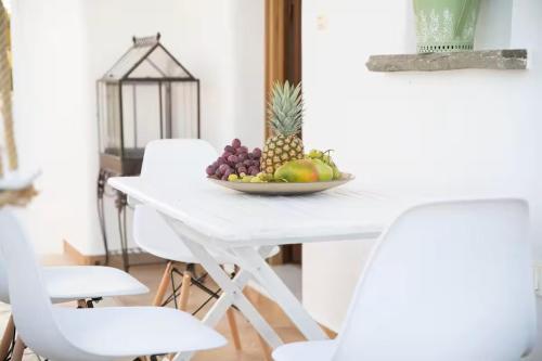 a white table with a bowl of fruit on it at Zoe & Zen Collection in Kampos Paros