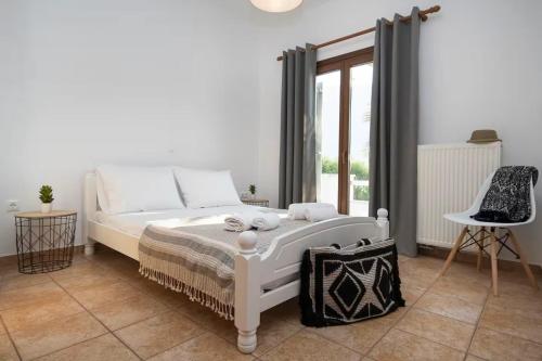 a bedroom with a white bed and a window at Zoe & Zen Collection in Kampos Paros
