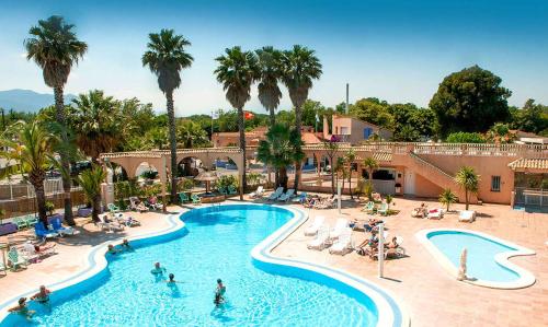 une piscine dans un complexe avec des palmiers et des personnes dans l'établissement Neptune 158 Argeles, à Argelès-sur-Mer