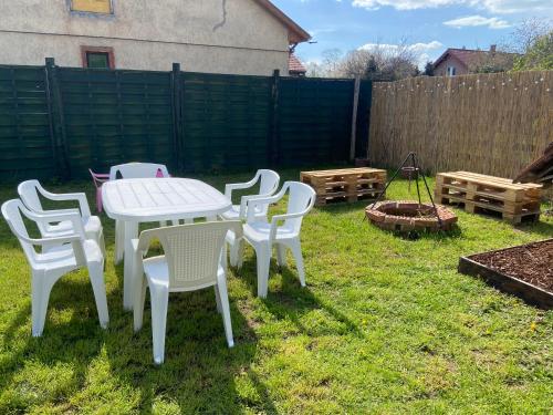 a white table and chairs in a yard at Kollar apartman in Balatonszemes