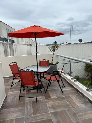 a table and chairs with a red umbrella on a balcony at Hermosa casa alberca climatizada in San Baltasar