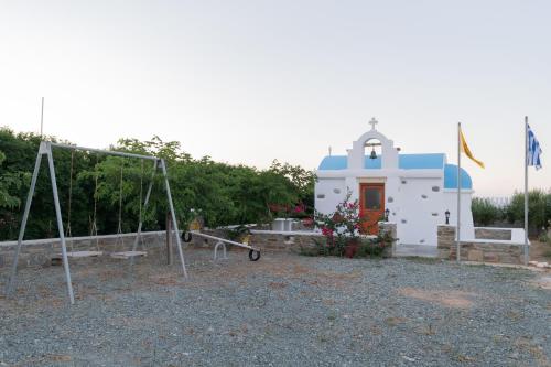 a small white chapel with a playground in front of it at Zoe & Zen Collection in Kampos Paros