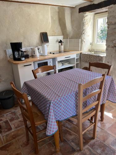 une cuisine avec une table, des chaises et une nappe dans l'établissement Cabanon entouré de montagnes et d'oliviers, à Nyons