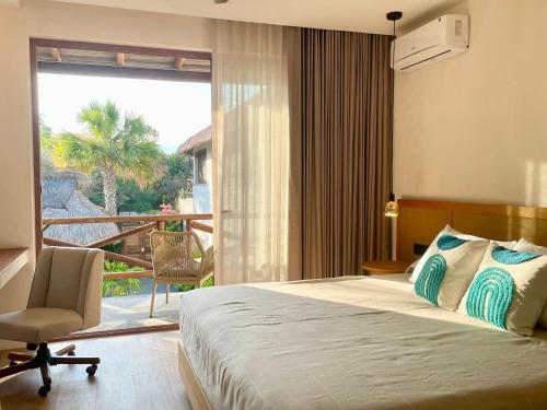 a bedroom with a bed and a chair and a balcony at Bidmont Villa Spa in Puerto Escondido