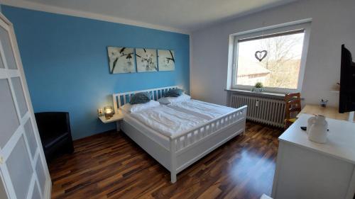een blauwe slaapkamer met een bed en een raam bij Fewo Flutbarke in Wilhelmshaven