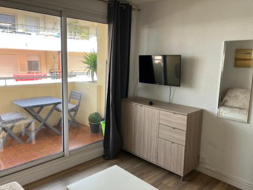 un salon avec une télévision à écran plat et une fenêtre dans l'établissement Superbe studio au bord de la mer à Sete, à Sète