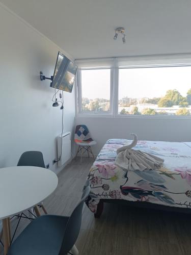 une chambre avec un lit, une table et une fenêtre dans l'établissement Kasa & Familia, à Valdivia