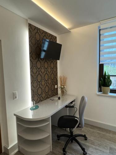 a white desk with a chair and a tv on a wall at Landgasthof & Hotel Waldeck in Treuen