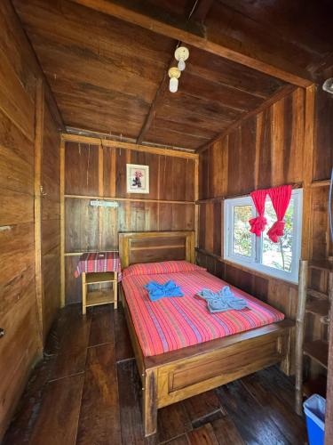 a bedroom with a bed in a wooden cabin at El Portal De Champey in Lanquín