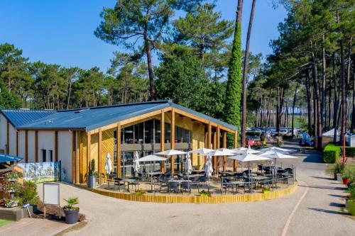 un restaurant avec des tables et des parasols en face de celui-ci dans l'établissement Les Dunes de Contis 4 étoiles à St Julien en Born emplacement 277 3CH 1SDB 8 personnes, à Saint-Julien-en-Born