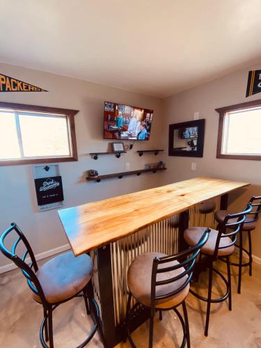 a bar in a room with three chairs and a television at Green Bay Packer Game House or Resch Expo less than 1 mile from Lambeau Field in Green Bay