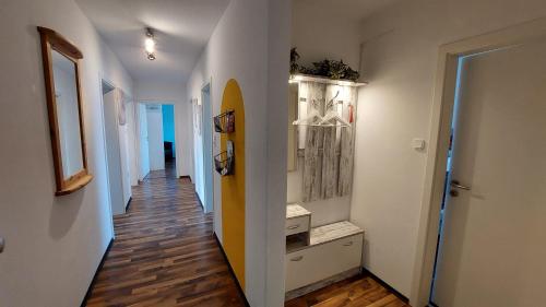 een hal met witte muren en houten vloeren en een hal met een surfplank bij Fewo Flutbarke in Wilhelmshaven