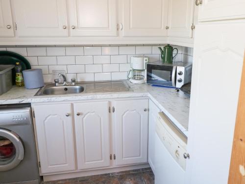 a kitchen with white cabinets and a sink at Realt na Maidne in Claddaghduff