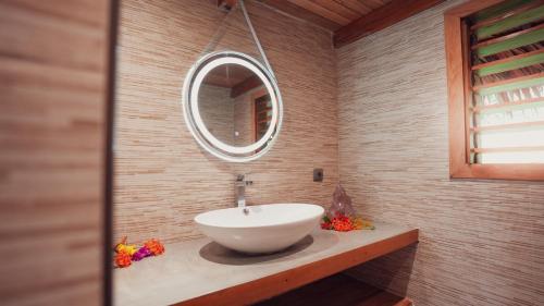 a bathroom with a white sink and a mirror at Manja Kely Lodge in Nosy Be