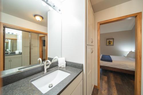 a bathroom with a sink and a mirror and a bed at Ski Run 303 by SummitCove Lodging in Keystone