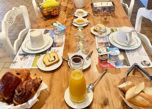 een houten tafel met ontbijtproducten en jus d'orange bij Le Clos de la Barre- Chambres d'hôtes de charme en Normandie-BASLY-Proche plage débarquement in Basly