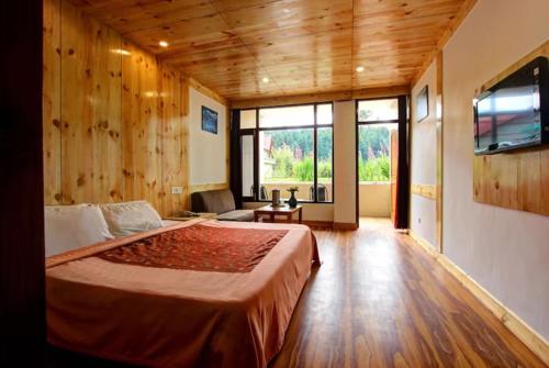 a bedroom with a large bed and a large window at Hotel Premium Conifer Manali Near Hadimba Devi Temple - BEST HOTEL IN MANALI in Manāli