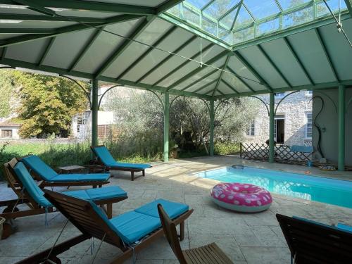 a patio with chairs and a swimming pool at Domaine Spa Perret-3Ha-Château ArtDéco MasterSuite B&B ou Gîte de Charme-À3Mn Giverny-Jardins Monet-Le Vexin-Piscine Chauffée en Haute Saison-Aire Enfants-PingPong-Options Dîner-Billard-Massage-Yoga-Coaching-Fitness-Sauna-Hammam-Promo2Nuits Jacuzzi inclus in Sainte-Geneviève-lès-Gasny