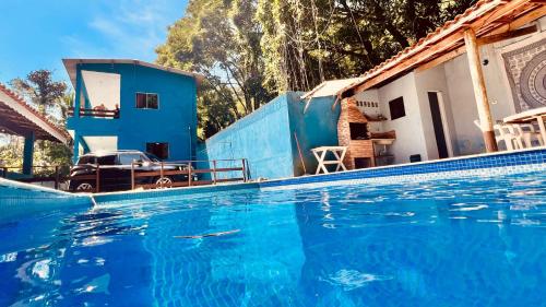 a blue swimming pool in front of a house at Suites Oceano in Caraguatatuba
