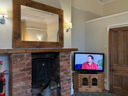 a television sitting on a fireplace in a living room at Hargate Hall Self Catering in Buxton