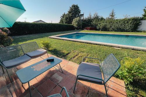 un patio avec deux chaises et une table à côté d'une piscine dans l'établissement Calme et Confort sur les Hauteurs de Montauban, à Montauban