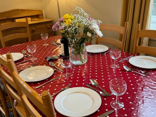a table with plates and glasses and a vase of flowers at Hargate Hall Self Catering in Buxton