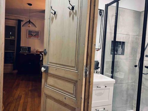 La salle de bains est pourvue d'une douche et d'une porte en bois. dans l'établissement Paris 15 - Porte de Versailles, Salon des expositions - Cosy studio, à Paris