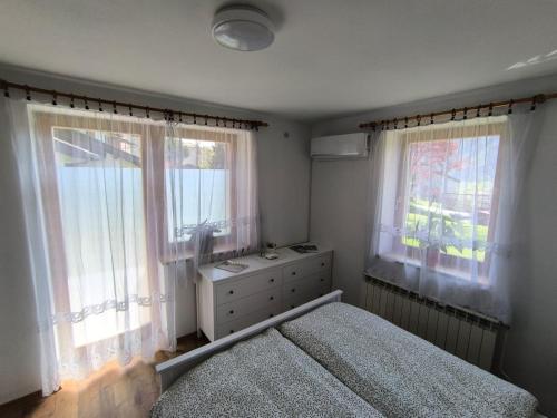 a bedroom with a bed and two windows at Apartma Pri noni Silvi in Tolmin