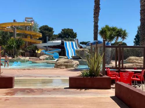 une piscine avec un toboggan aquatique dans un complexe hôtelier dans l'établissement Mobil Home 6 personnes La Marina, à Canet