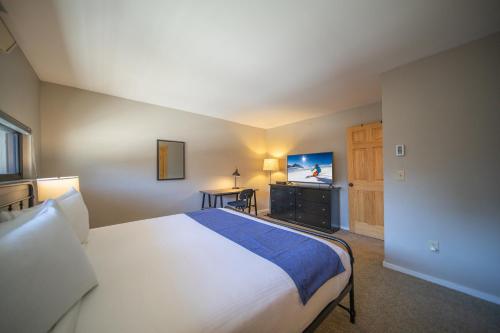 a bedroom with a large bed and a television at Plaza 1408 by SummitCove Lodging in Keystone