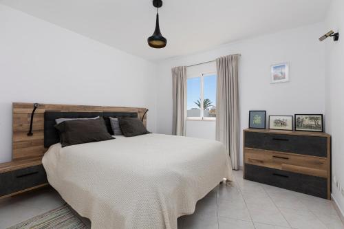 a white bedroom with a large bed and a window at Apartment Estrelícia Direct beach access in Porches