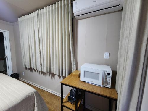 a bedroom with a microwave on a table next to a bed at Pousada Vilas Boas - Suíte Casal 1 in Cavalcante