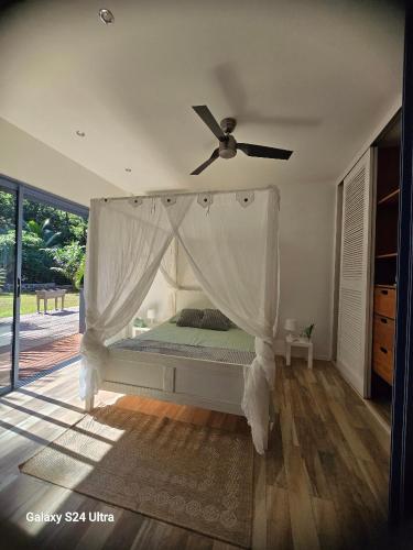 une chambre avec un lit avec un ventilateur de plafond dans l'établissement La Belle Dame, à Deshaies