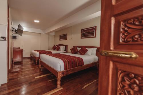 two beds in a room with wooden floors at Quechua Hotel Cusco in Cusco