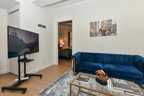 a living room with a blue couch and a flat screen tv at The Wolf of Wall Street Apartment in New York