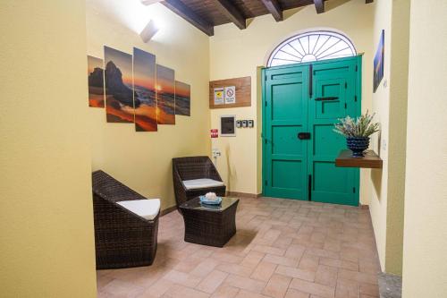 a hallway with a green door and chairs and a table at ISLAVENTO case vacanza Trapani in Trapani
