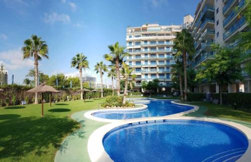 a resort with two pools and a large building at PRIMERA LINEA de PLAYA SAN JUAN en ALICANTE in Benimagrell